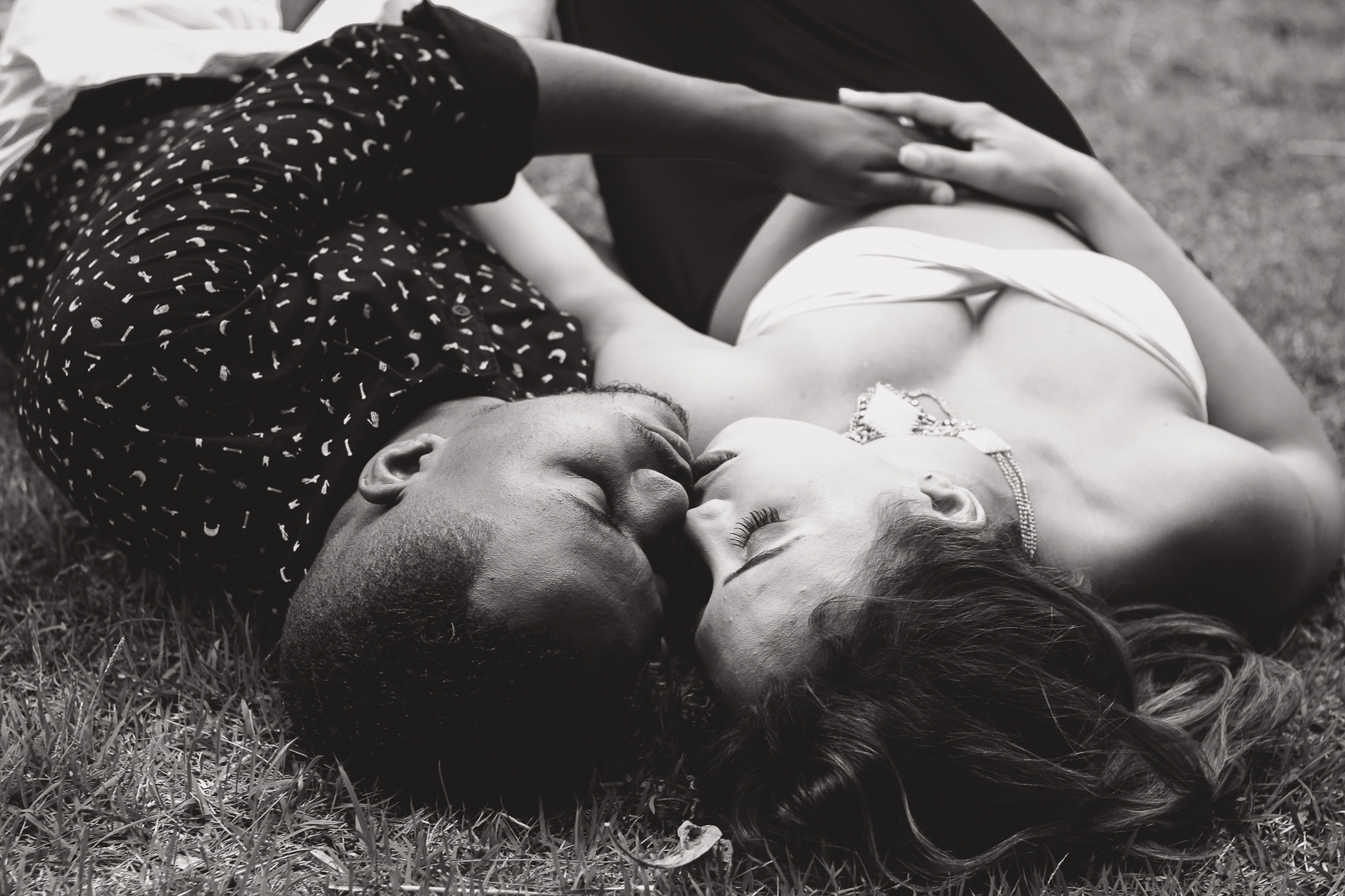 gryscale photo of couple lying on grass field