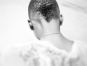 grayscale photography of the back of the person with necklace wearing shirt thumbnail