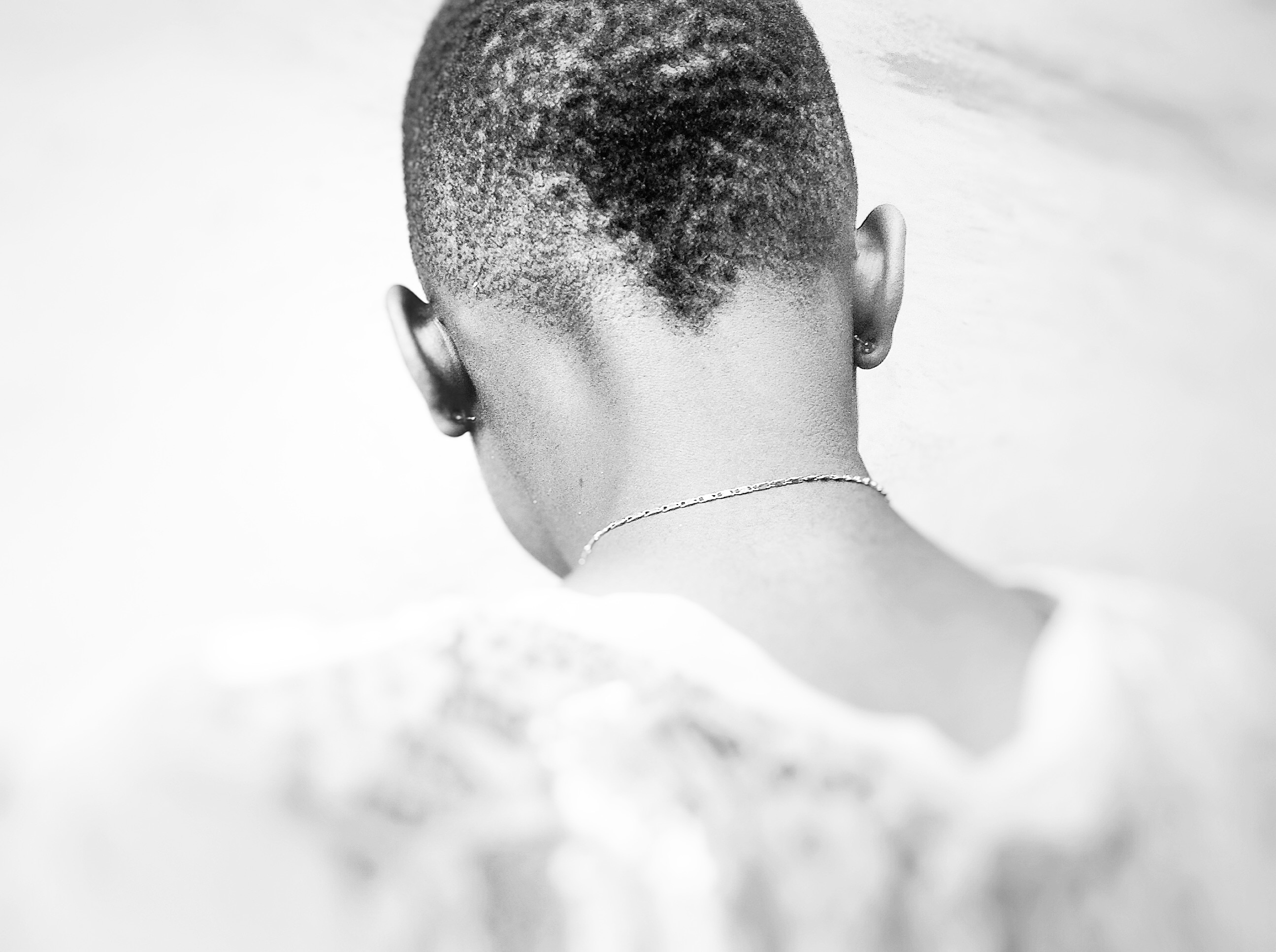 grayscale photography of the back of the person with necklace wearing shirt