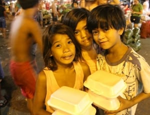 2 girl and boy holding white styro food container thumbnail