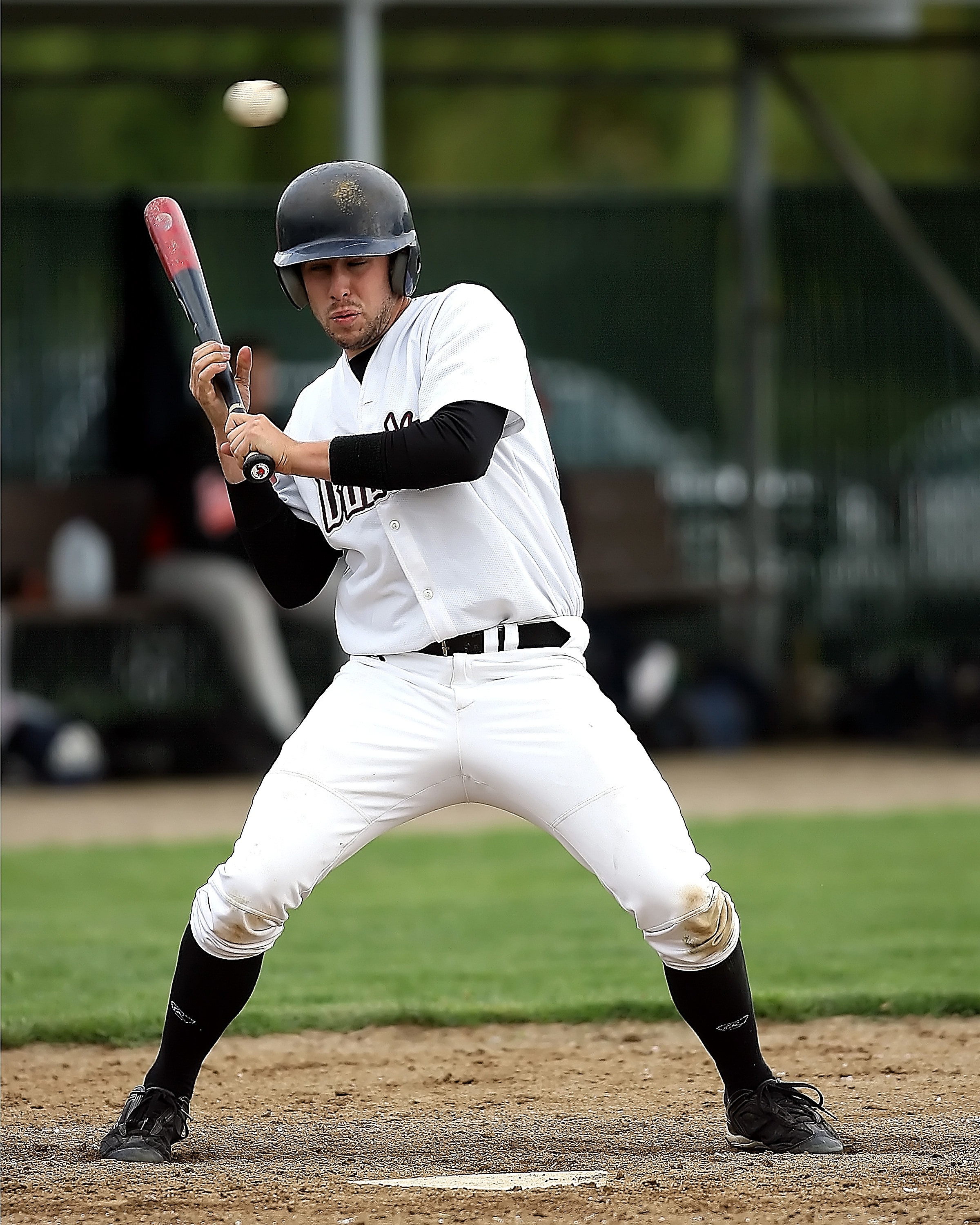 baseball player in white jersey holding black and red baseball bat