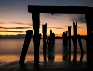 silhouette of wooden dock remains during sunset thumbnail