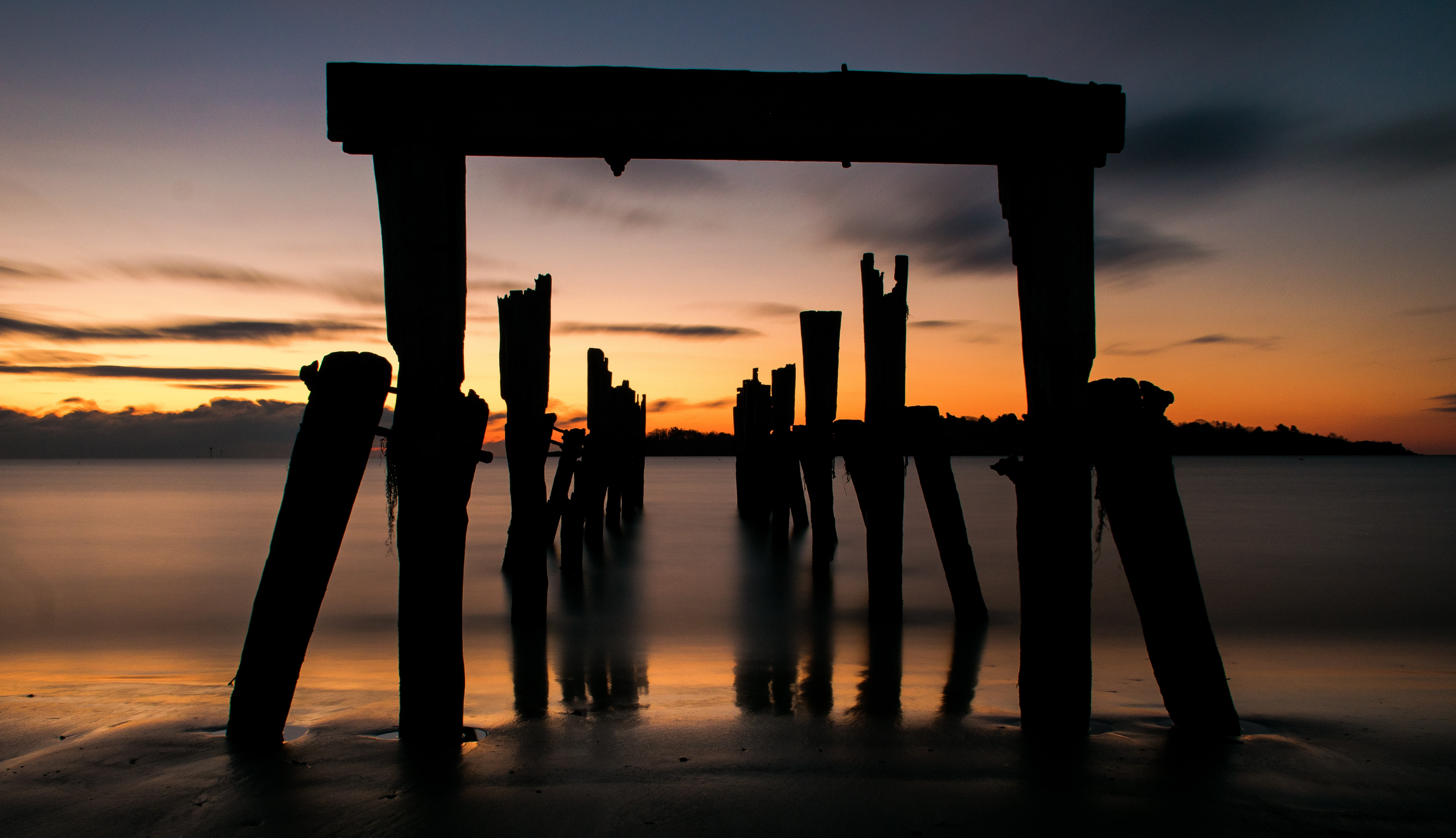 silhouette of wooden dock remains during sunset