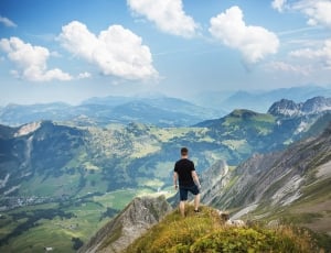 man wearing black t-shirt and pants while standing on mountain during daytime thumbnail