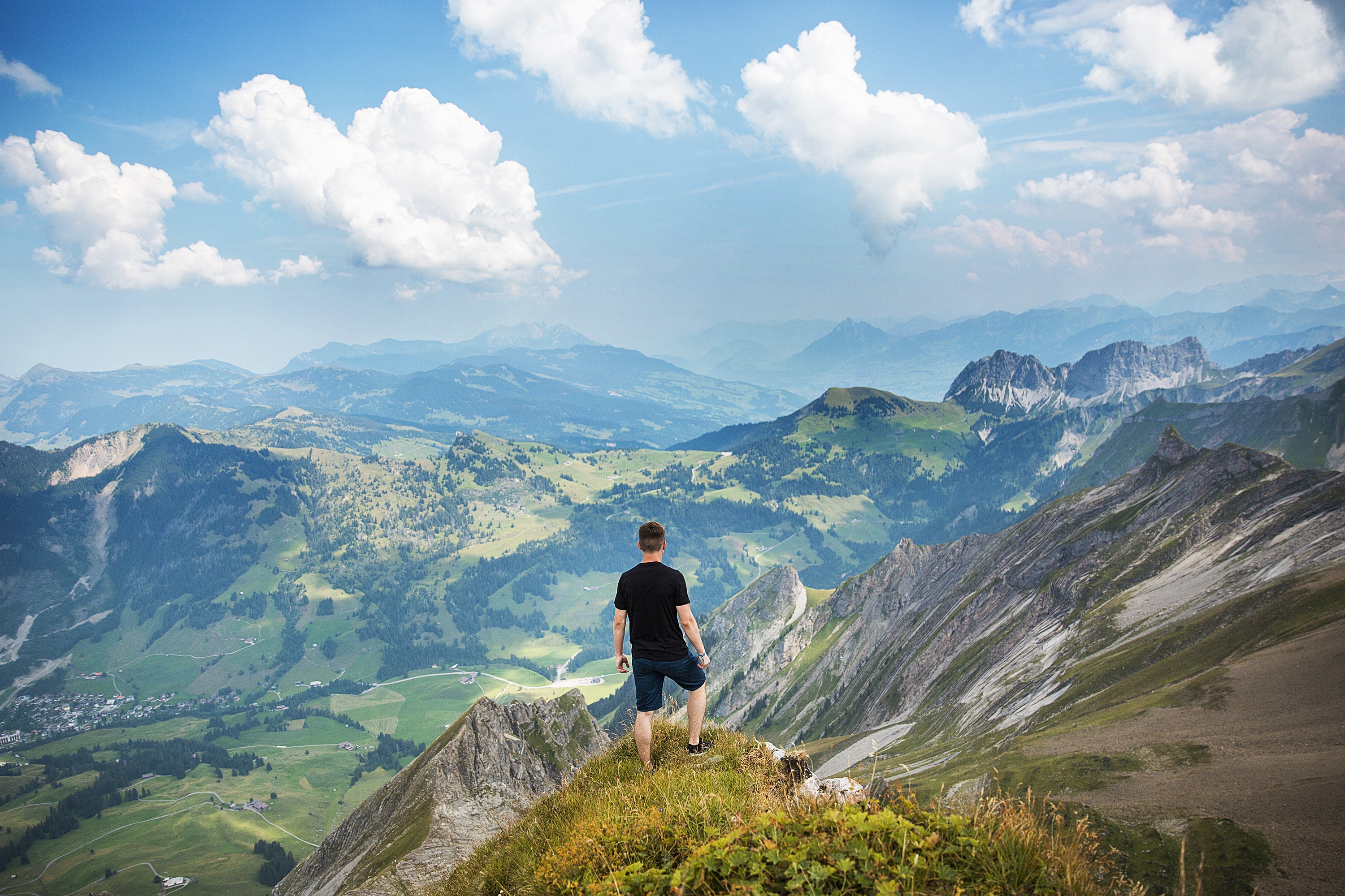 man wearing black t-shirt and pants while standing on mountain during daytime