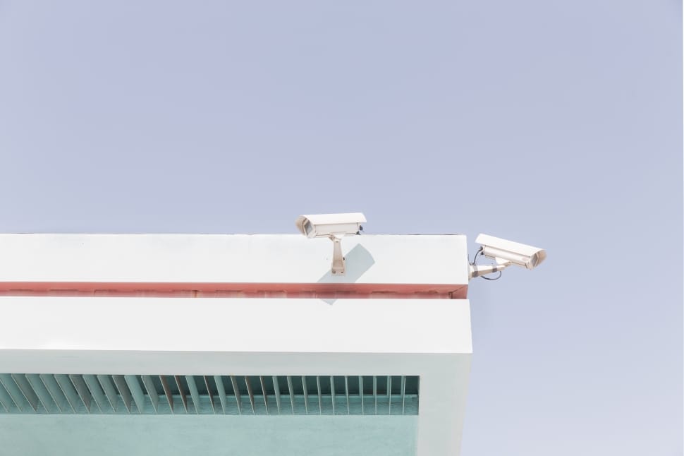 2 white bullet security cameras attached to wall at daytime preview