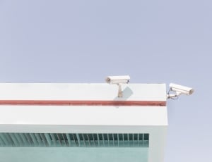 2 white bullet security cameras attached to wall at daytime thumbnail