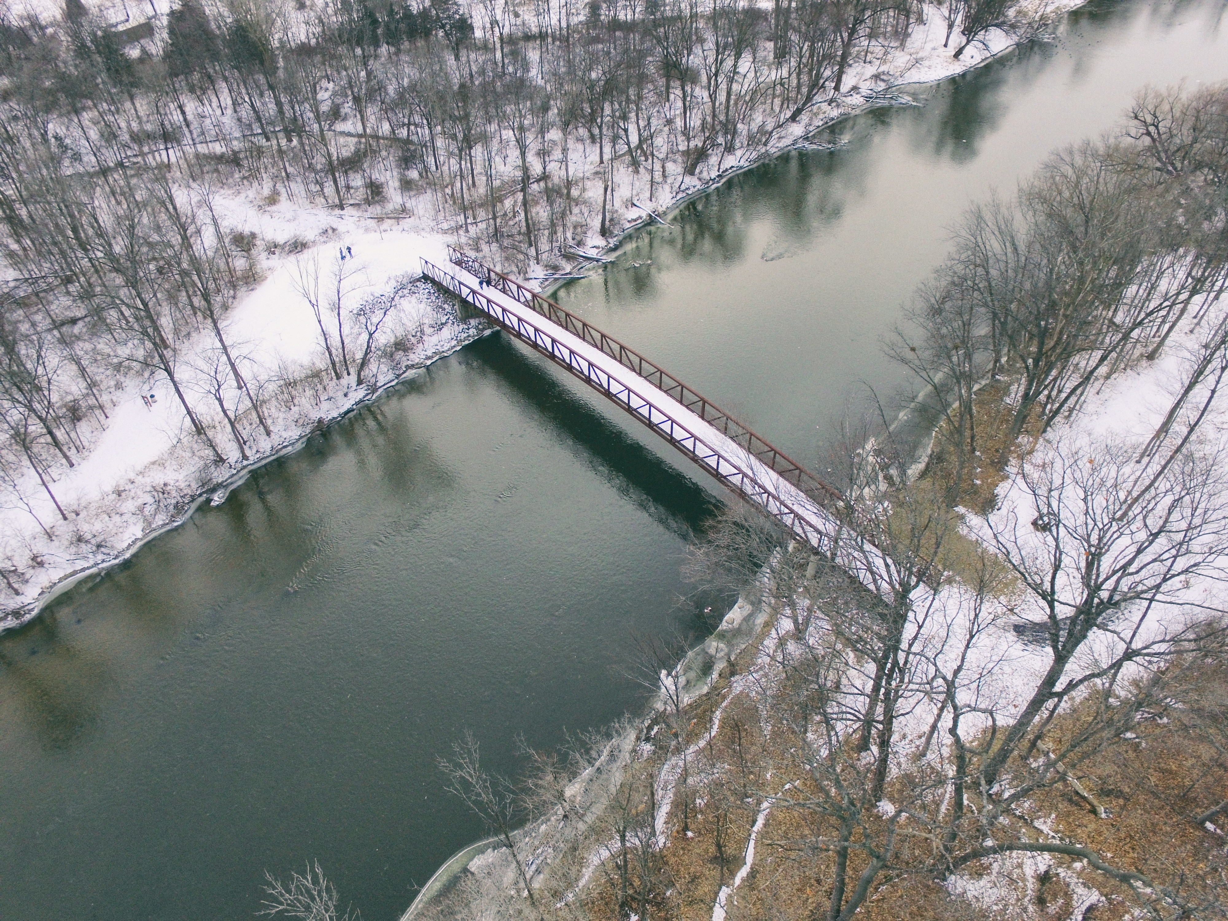 aerial photography of red metal bridge with road coated with snow