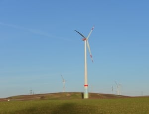 white and red wind turbines on green grass field at daytime thumbnail