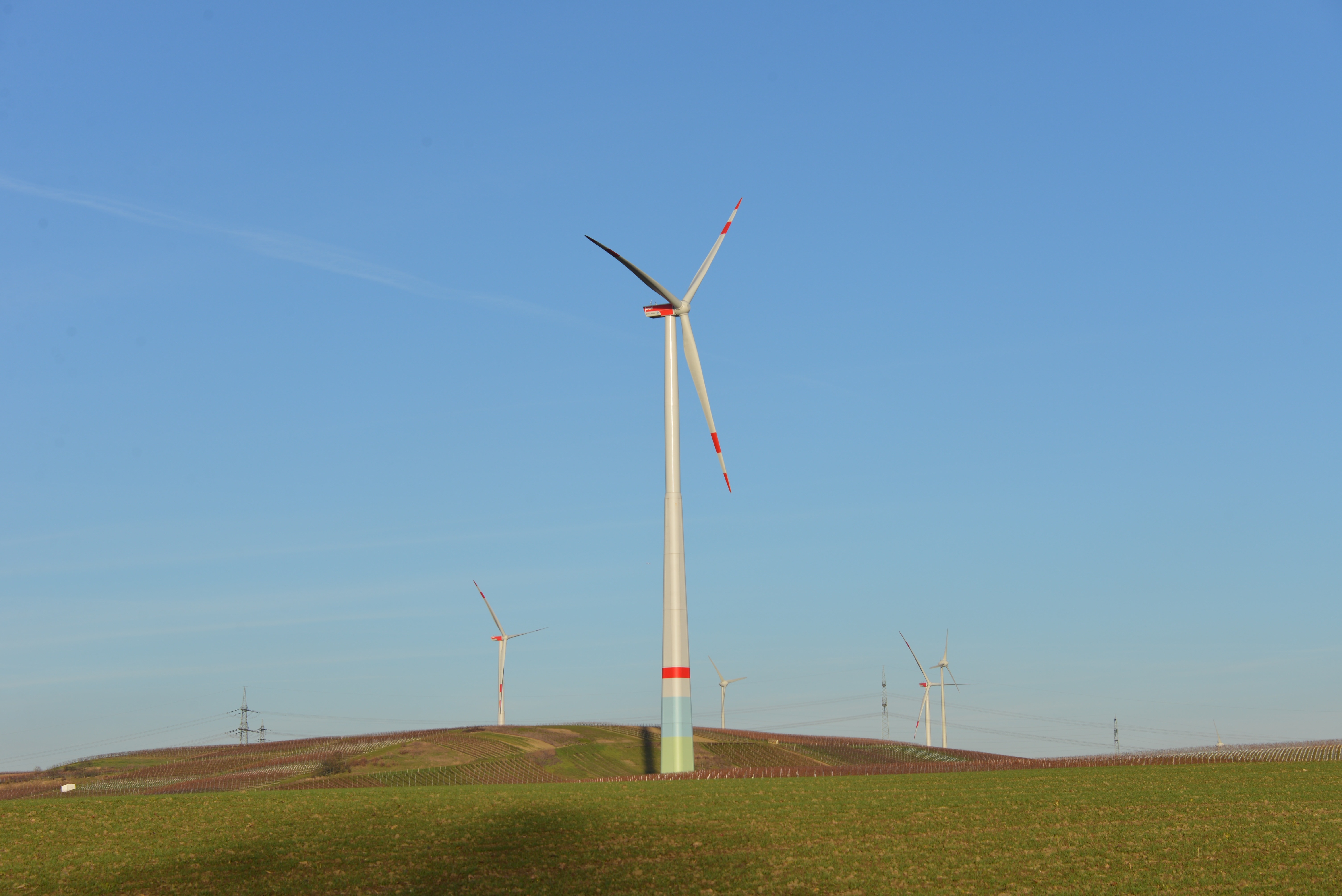 white and red wind turbines on green grass field at daytime