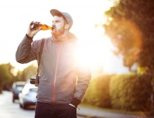 man wearing gray zip up jacket while drinking glas thumbnail