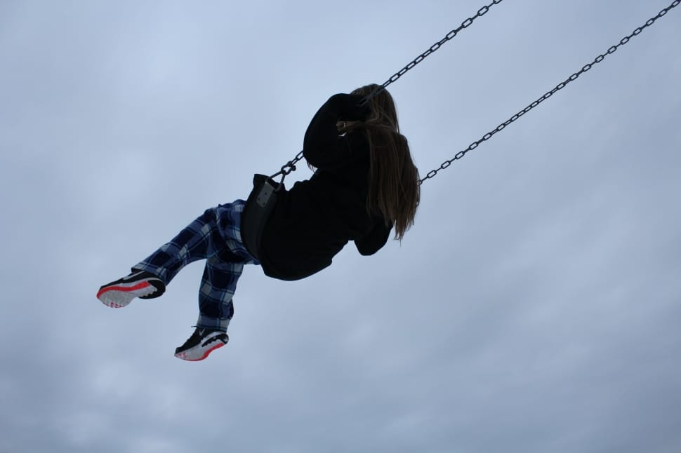 woman ride on swing under gray cloudy sky preview