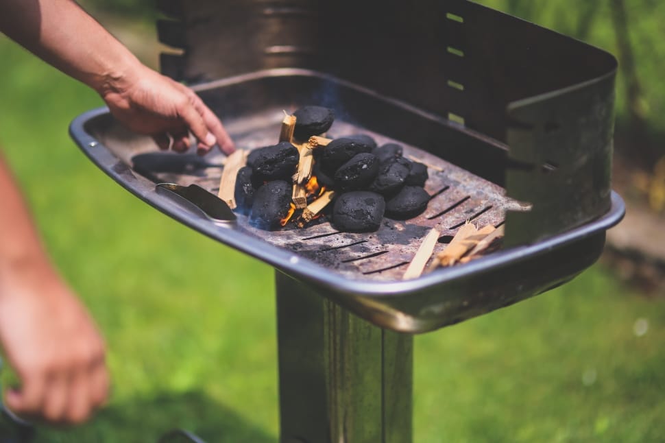 person heating charcoal on grill preview