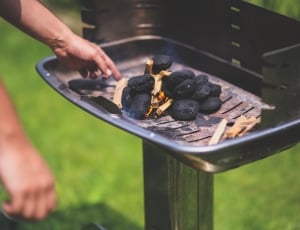 person heating charcoal on grill thumbnail