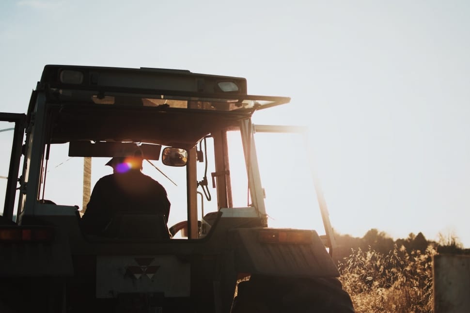 silhouette of man riding on a tractor during daytime preview