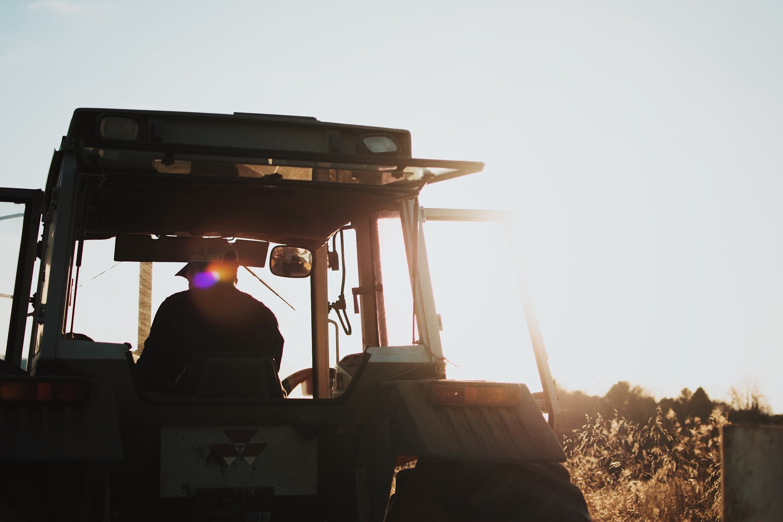 silhouette of man riding on a tractor during daytime