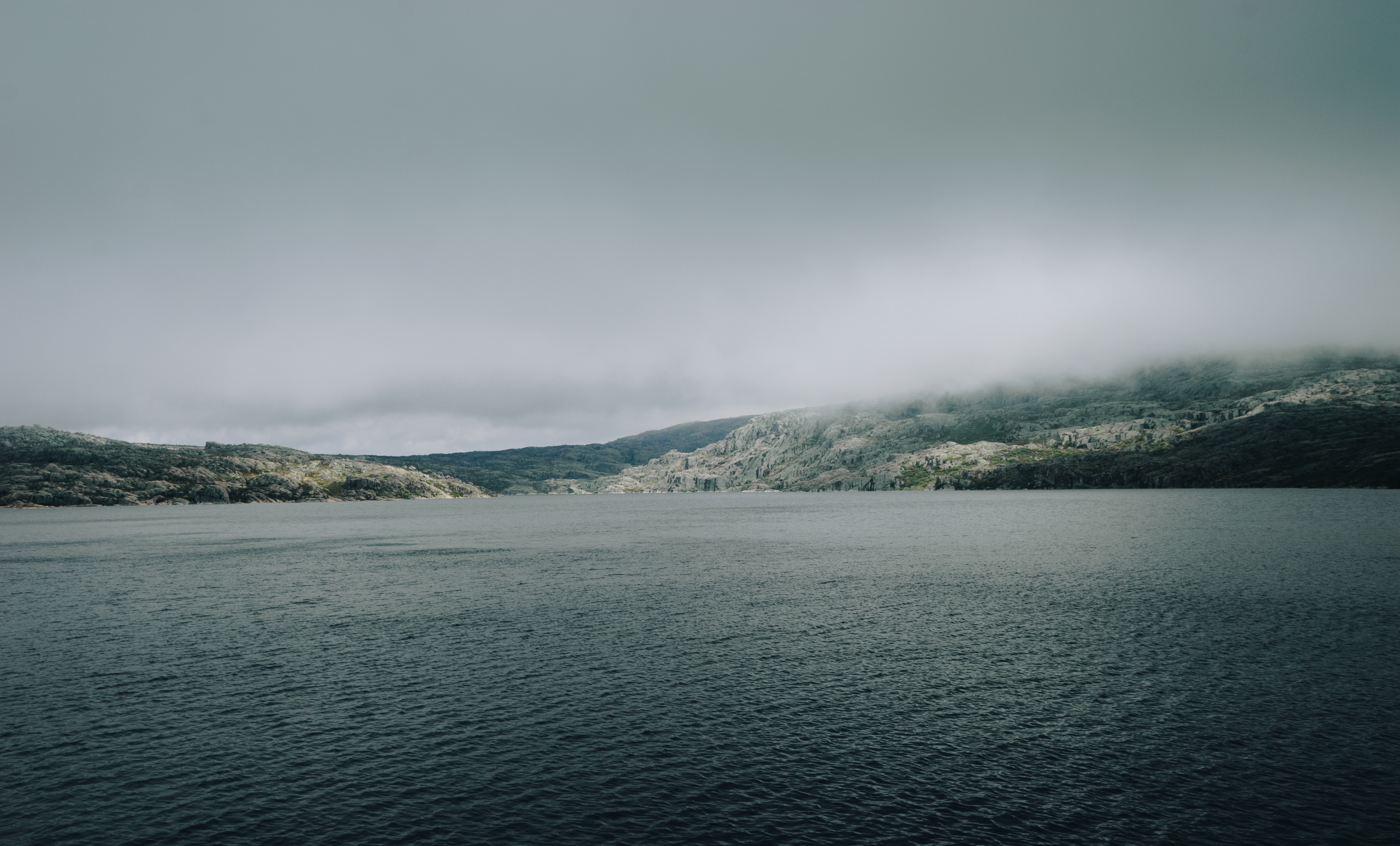 body of water and mountain under gray sky