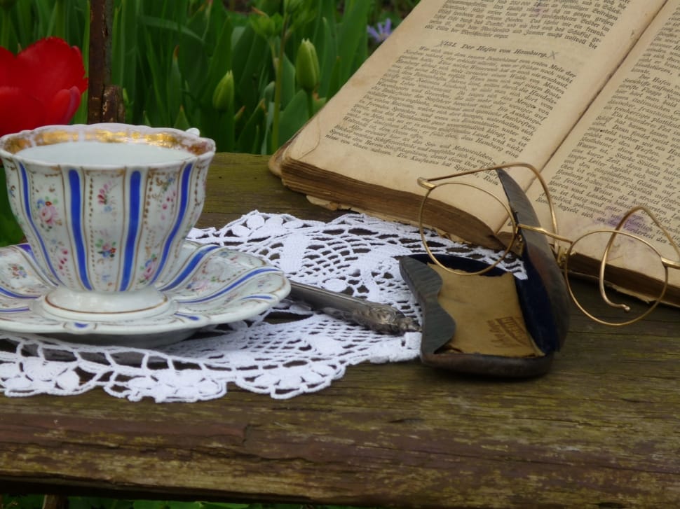 white and blue ceramic teacup set, brass framed bifocals and white knit doily preview
