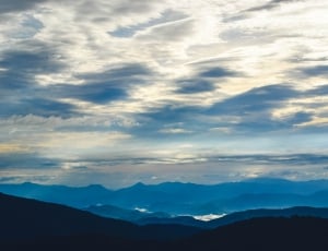 silhouette mountain under blue sky and white clouds thumbnail