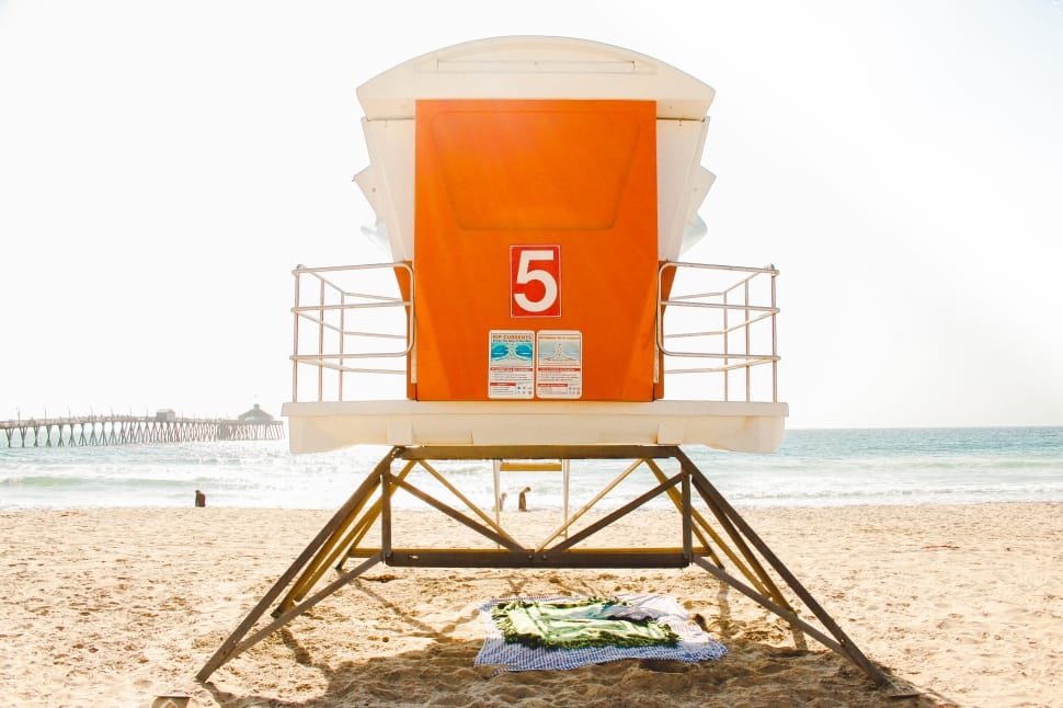 white and orange lifeguard post near seashore during daytime preview