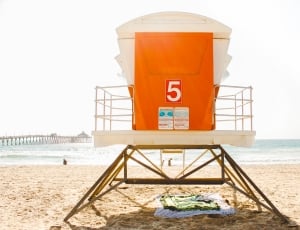 white and orange lifeguard post near seashore during daytime thumbnail