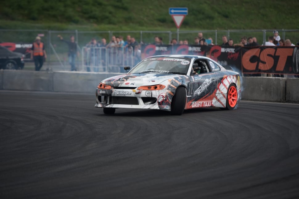 white, black, and orange race car on black concrete road preview