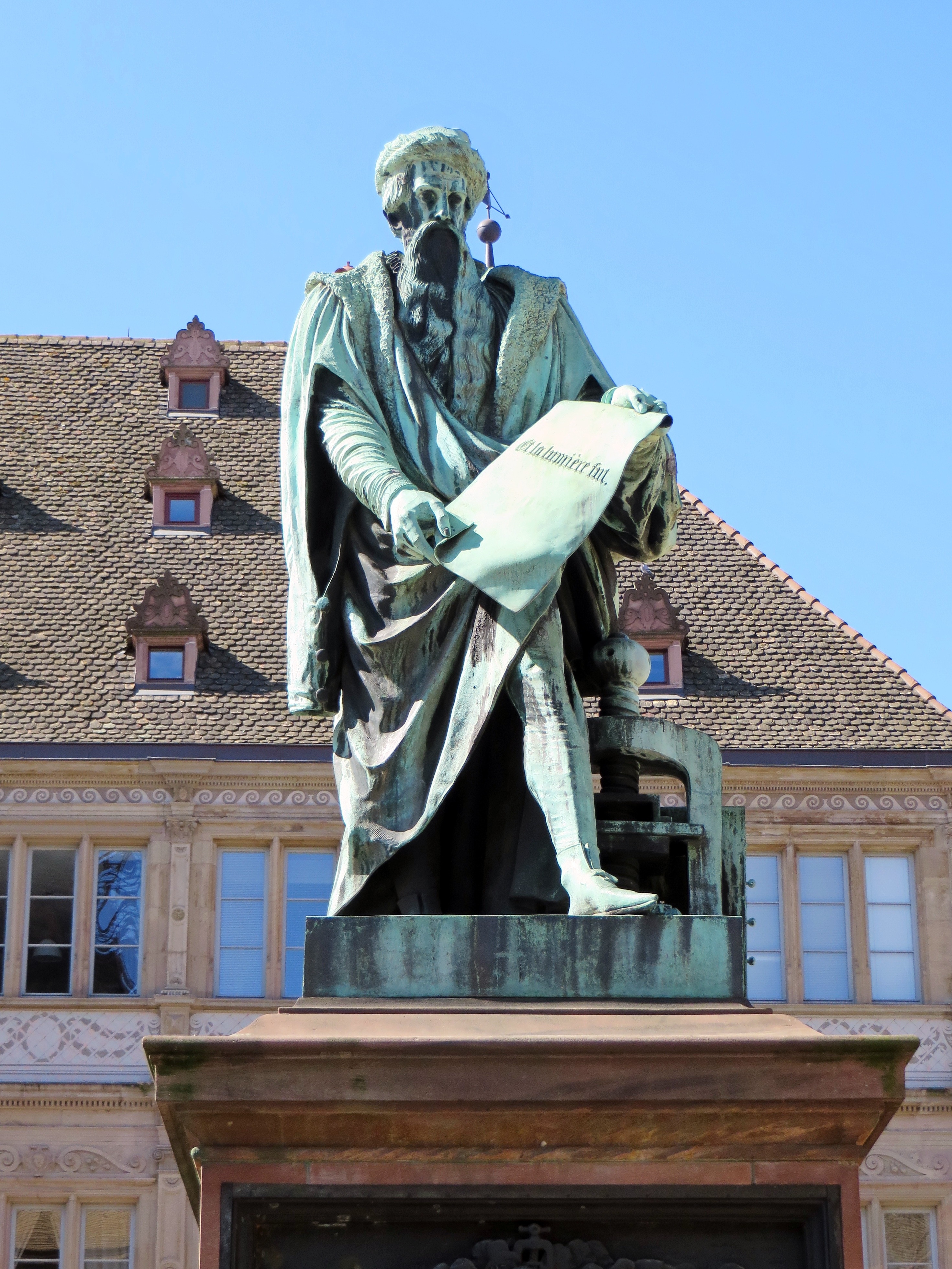 concrete man holding a scroll statue