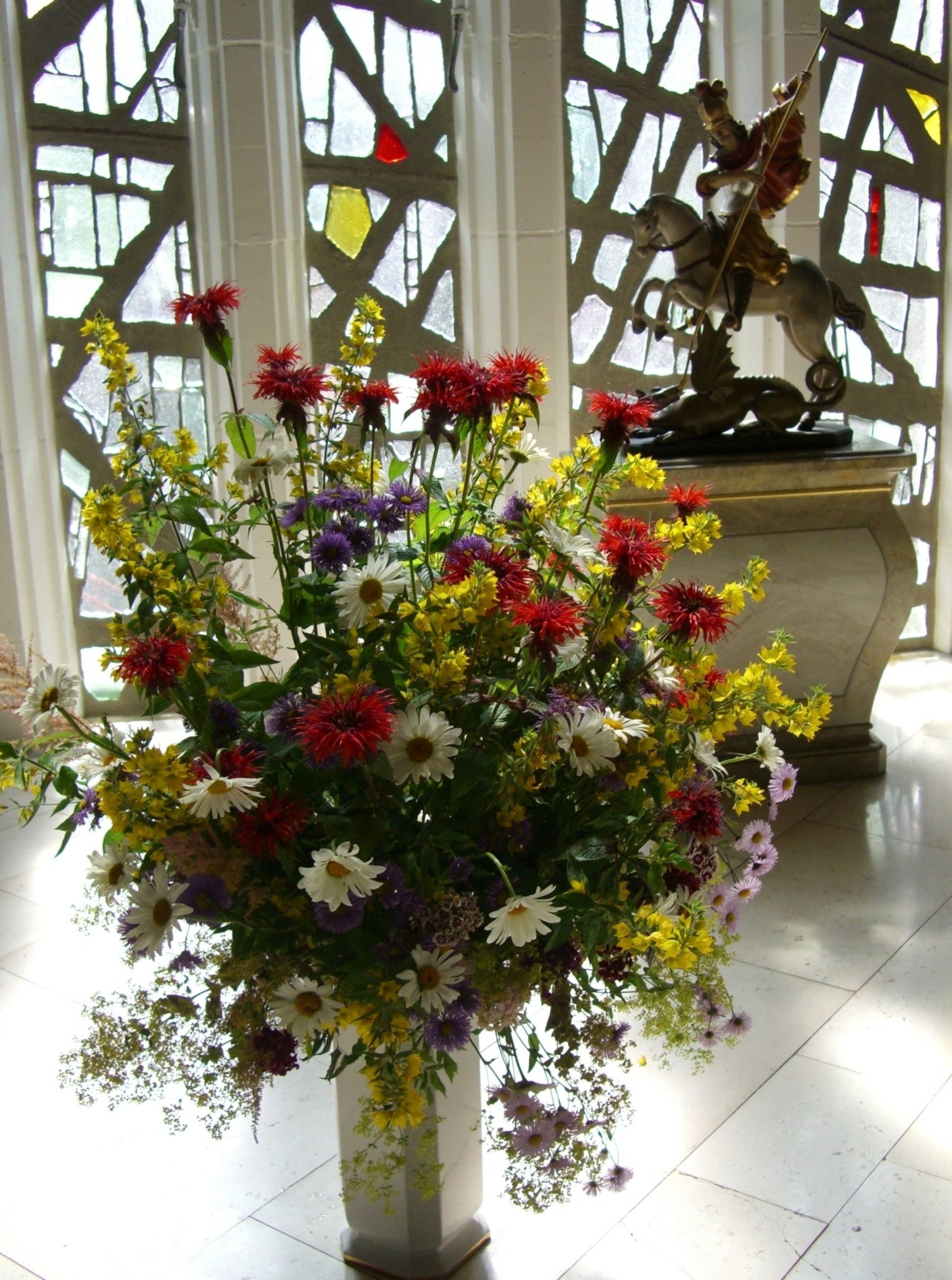 white, red, purple and yellow petaled flowers floral arrangement near man on horse statuette