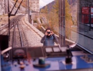 person blue vest taking photo of blue train thumbnail