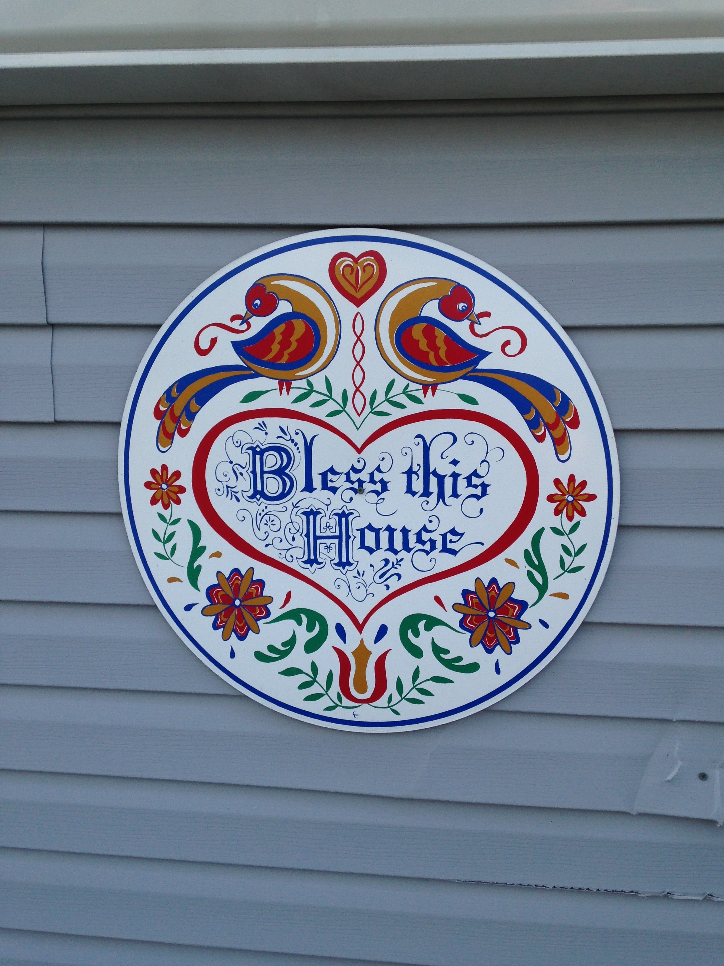 photo of round red and blue bless this home sign