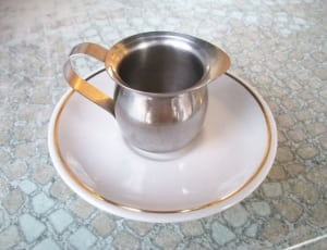 stainless steel teacup and white ceramic round saucer thumbnail