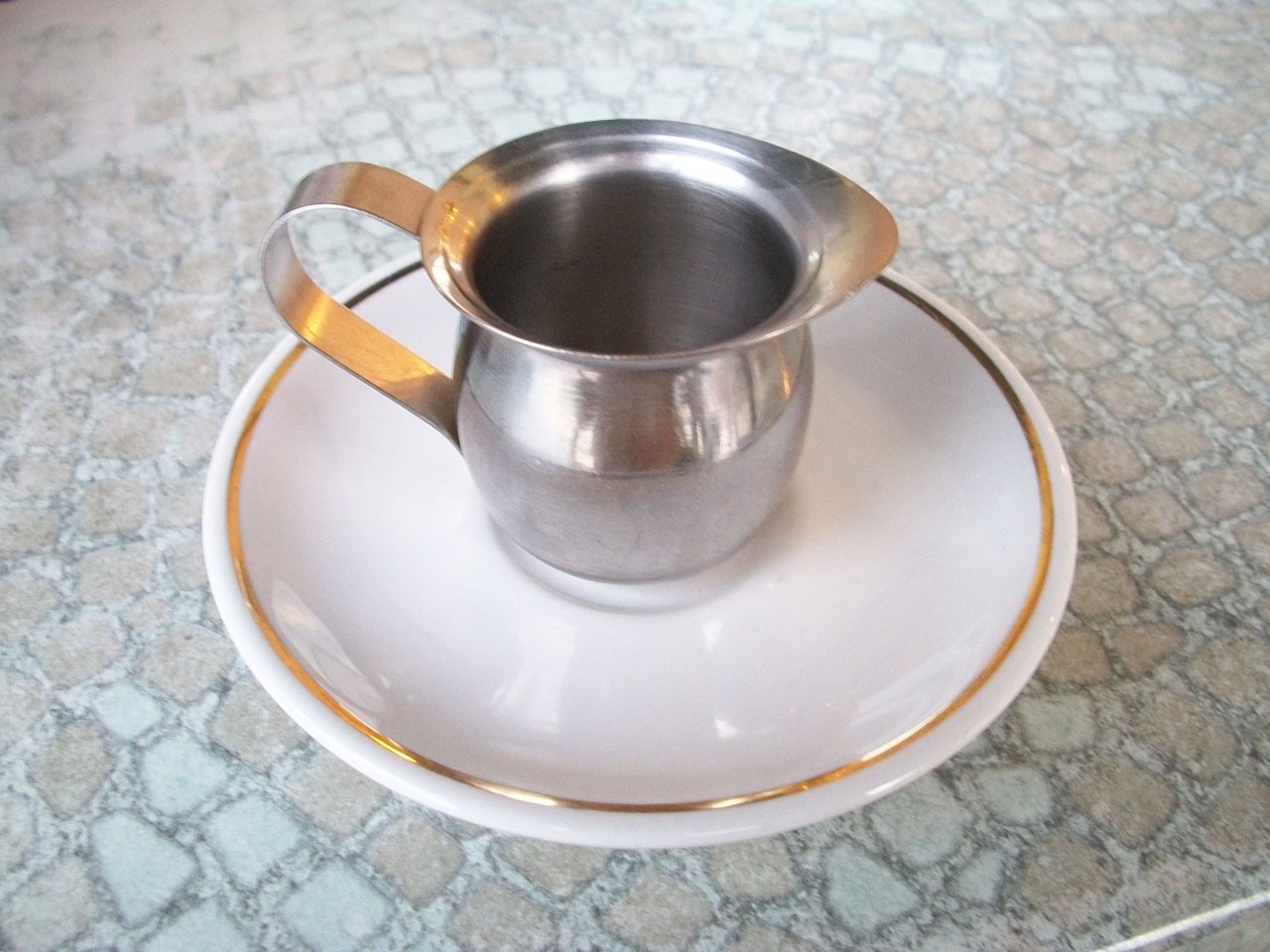 stainless steel teacup and white ceramic round saucer