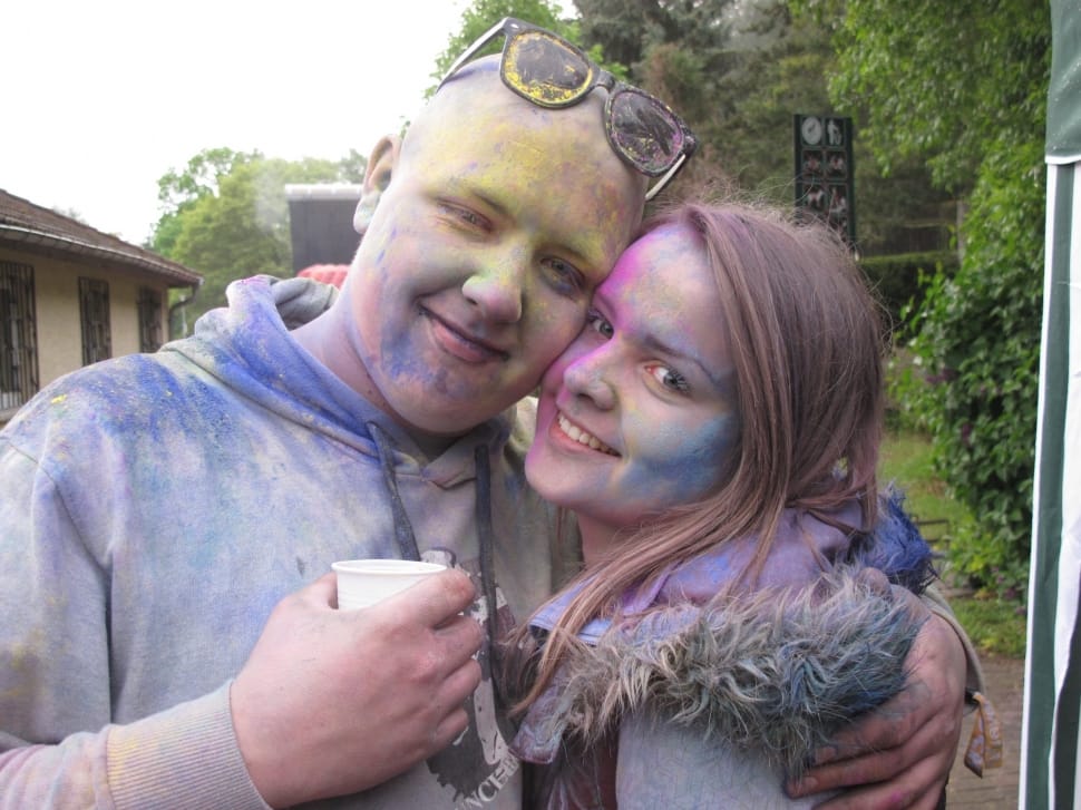 couple with color powder all over face and shirts embracing at daytime preview