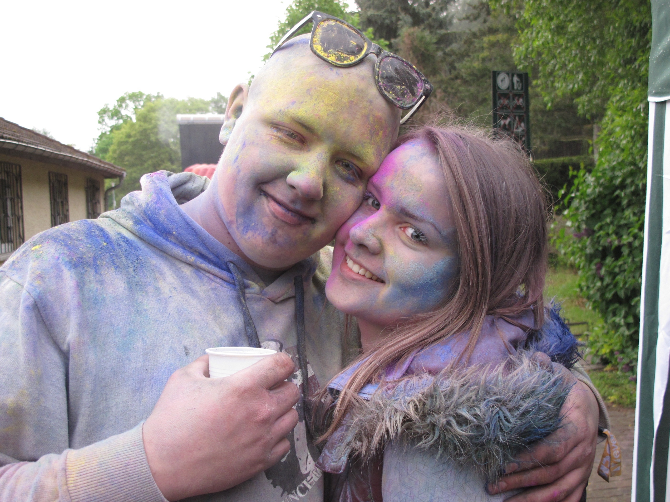 couple with color powder all over face and shirts embracing at daytime