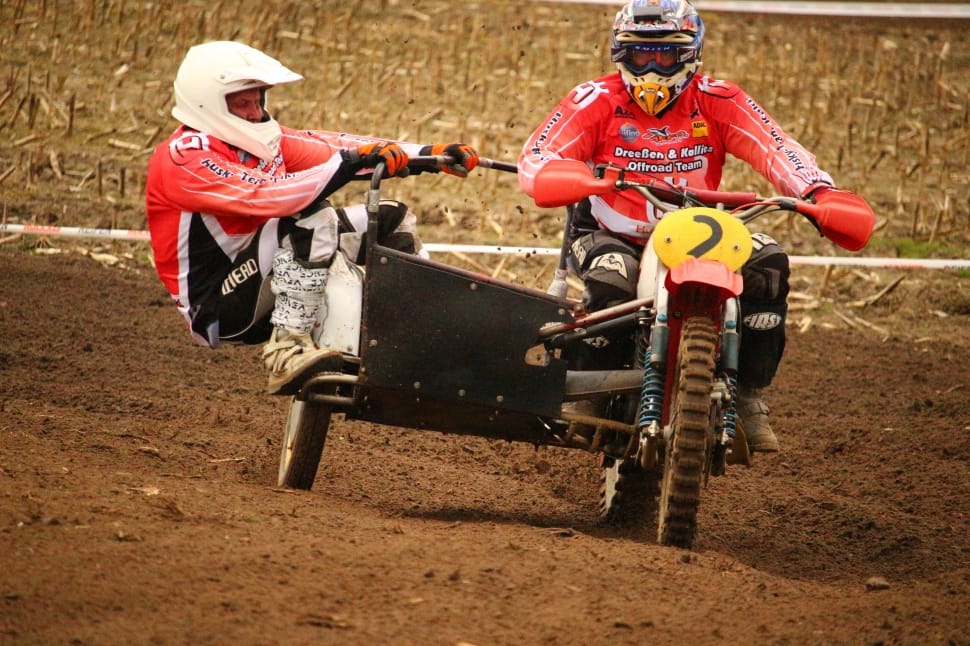 two riders riding on red and black motocross dirt bike with side trailer preview