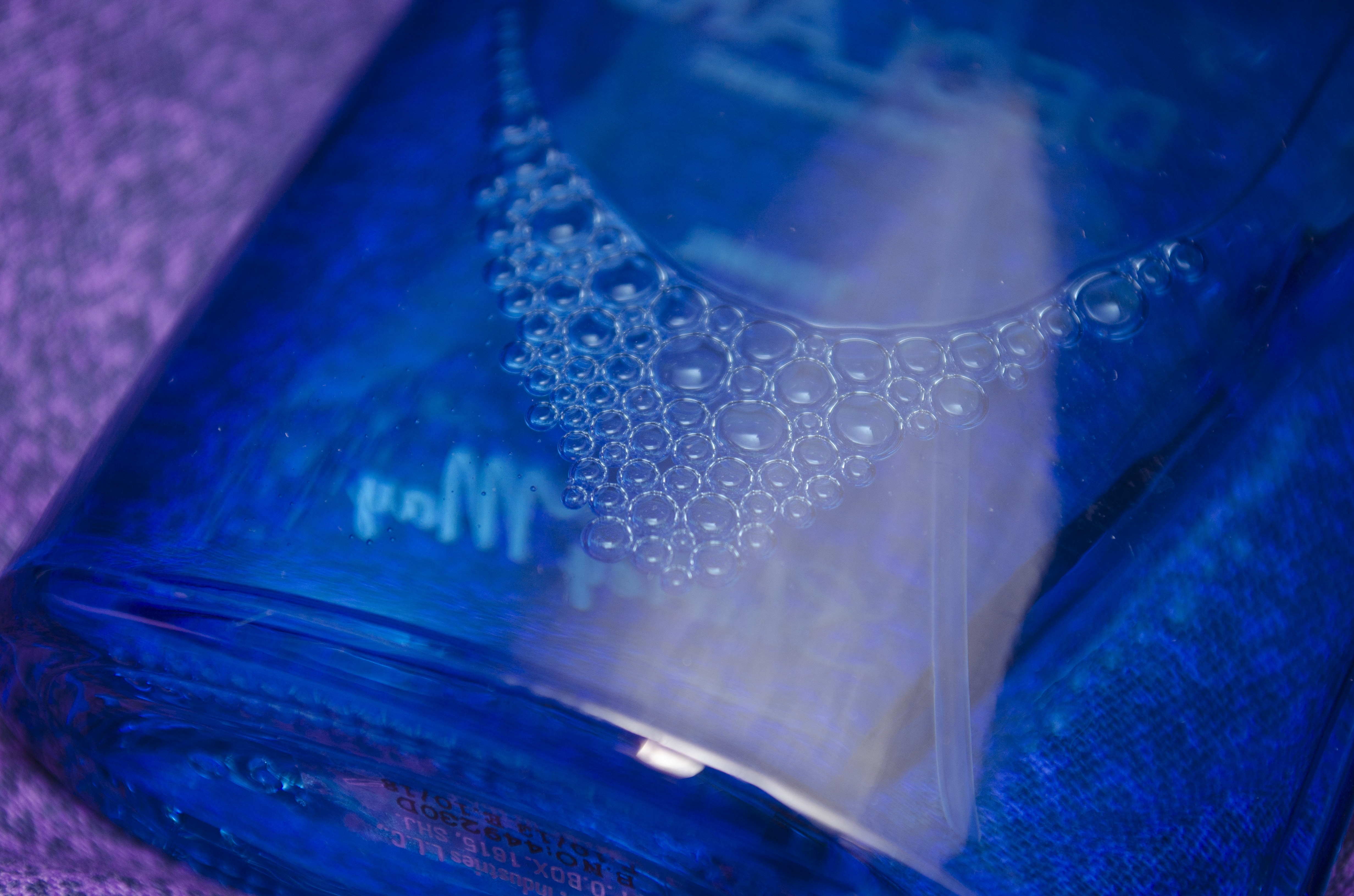 close up photography of bubbles inside blue bottle