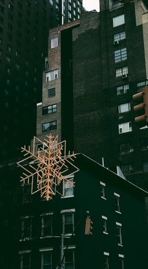 brown snowflake ornament hanging on black building thumbnail