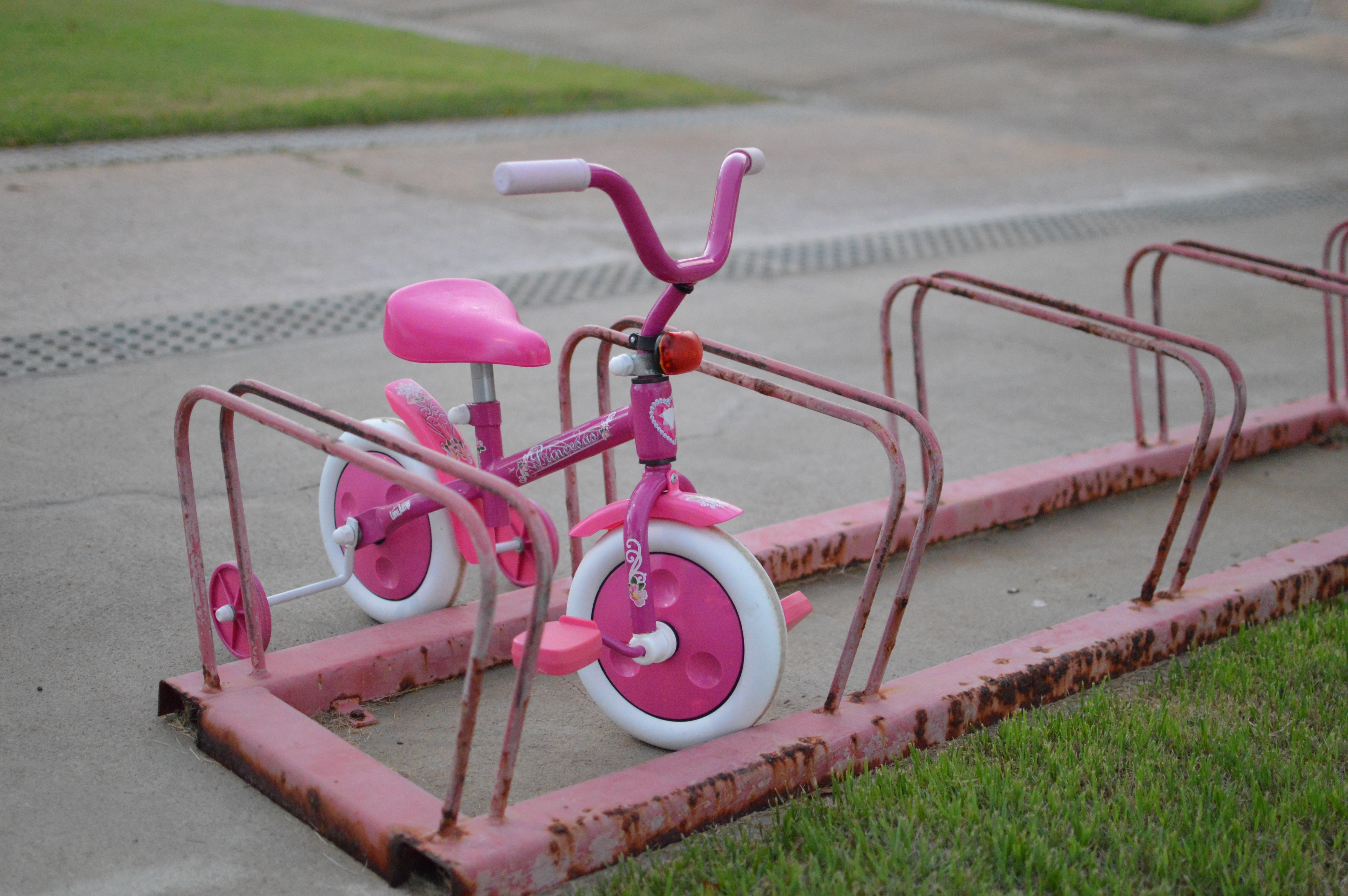 pink and white bicycle with training wheels