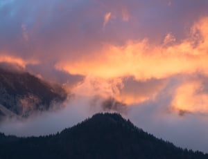 mountain covered with clouds under sunset during daytime thumbnail
