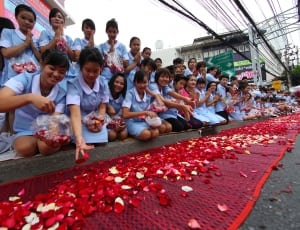 people in blue dress and shirt   kneeling near road throwing petals on red net photo thumbnail