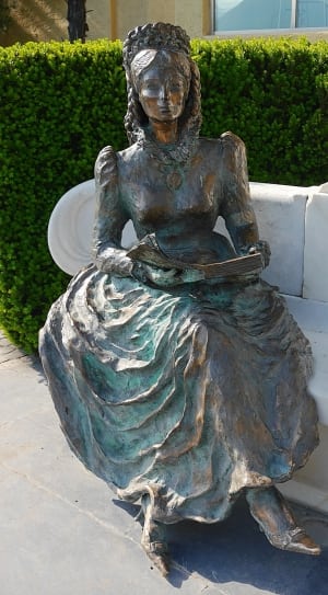 woman holding book statue under sunny sky thumbnail