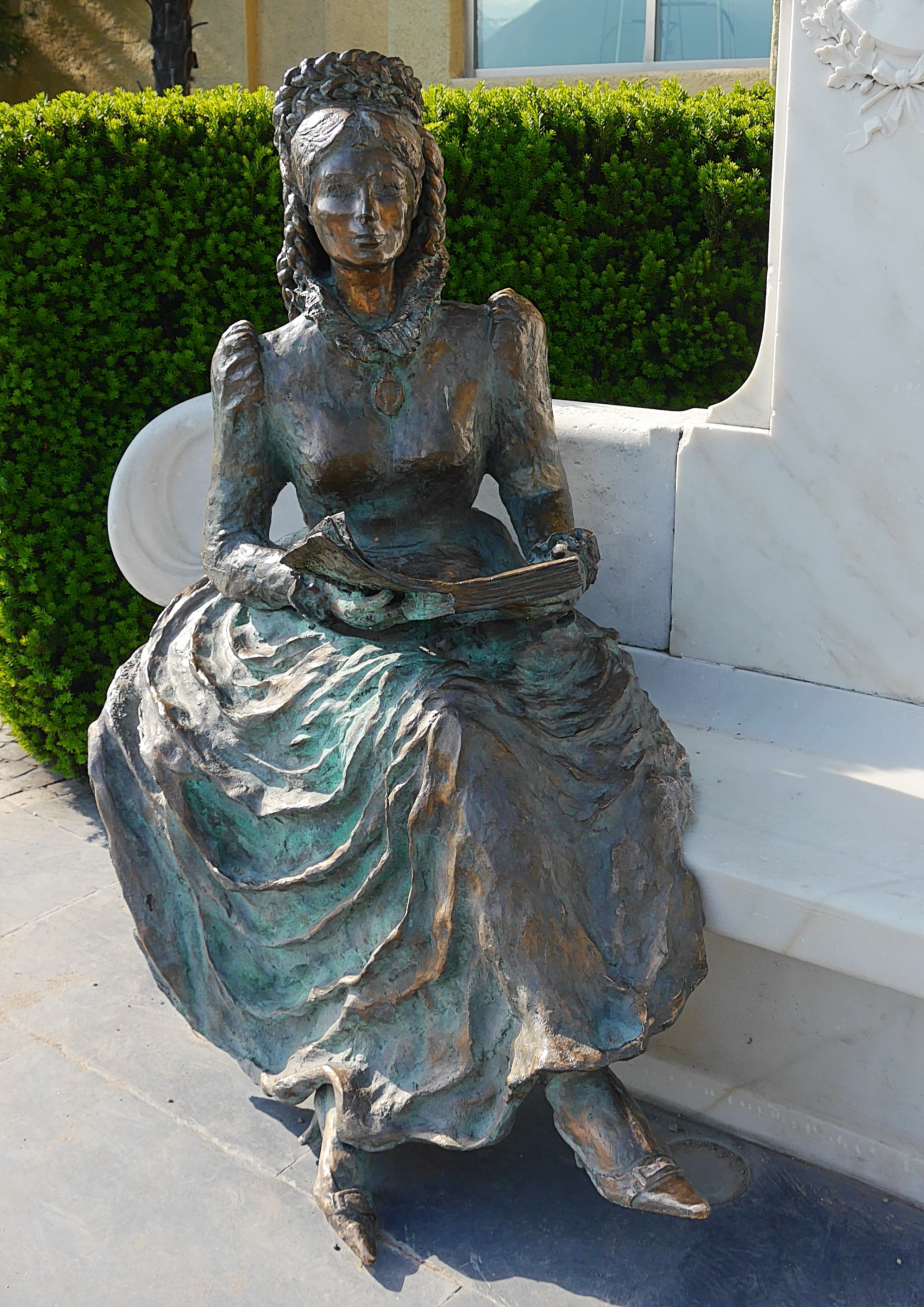 woman holding book statue under sunny sky