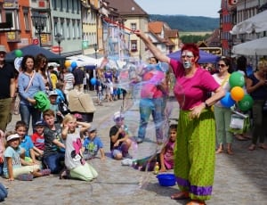 woman wearing clown costume performing a bubble trick in the street thumbnail