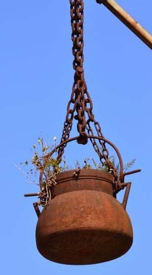 brown metal pot hanging on post with chains under blue sky during daytime thumbnail