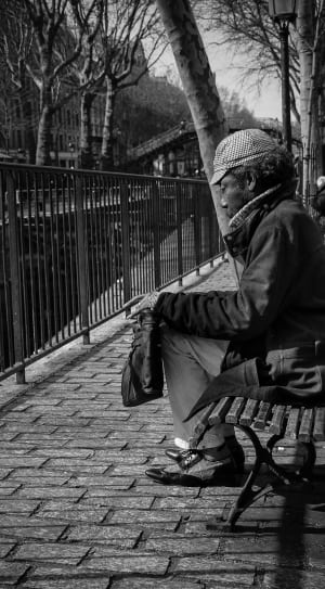 gray scale photo of man sitting on bench thumbnail