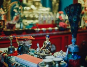 selective focus photograph of gold buddha figurine surround by various of items thumbnail