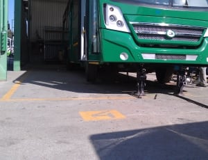 two black scissor jack under of green bus during day time thumbnail