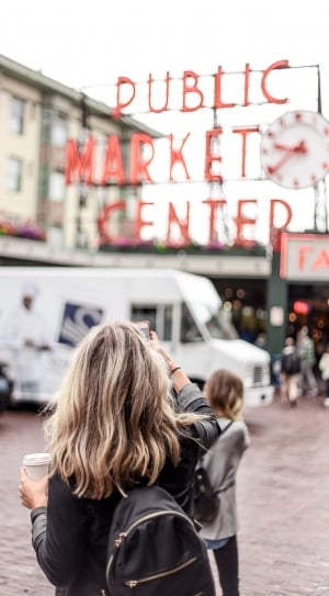 woman taking picture of public market center during daytime thumbnail