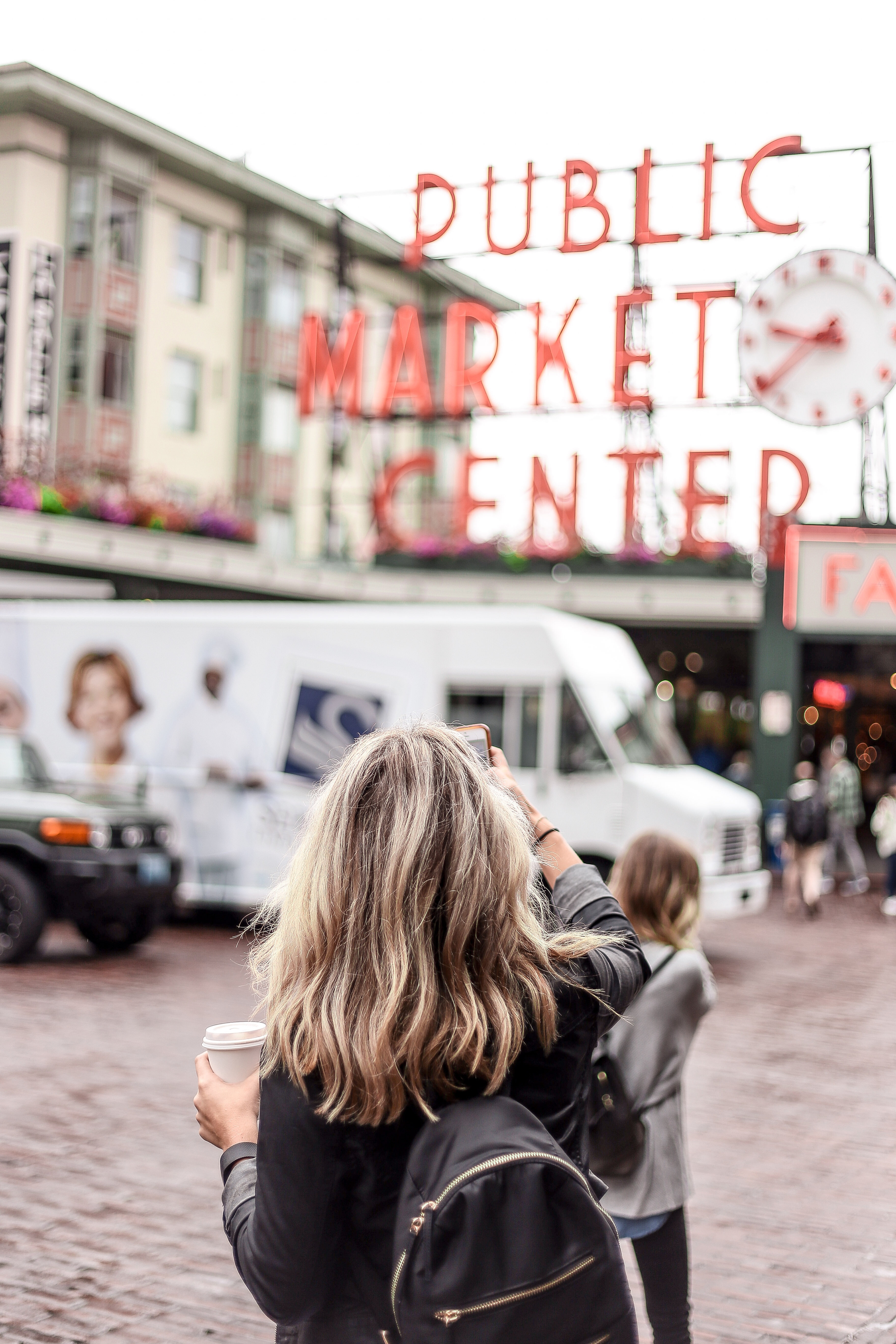 woman taking picture of public market center during daytime