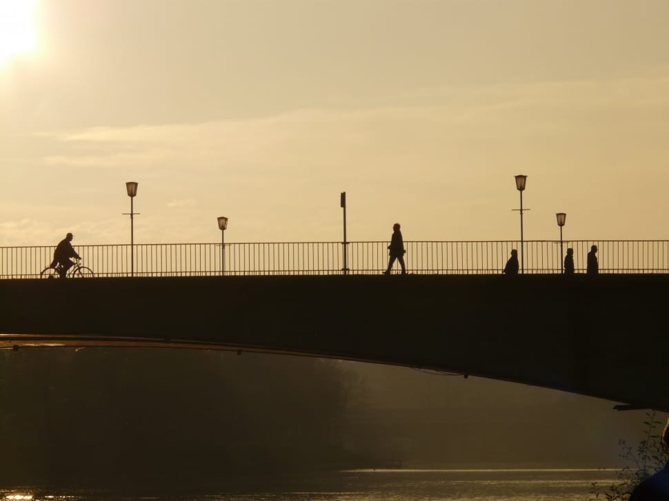 silhouette of bridge and people walking into it during daytime preview